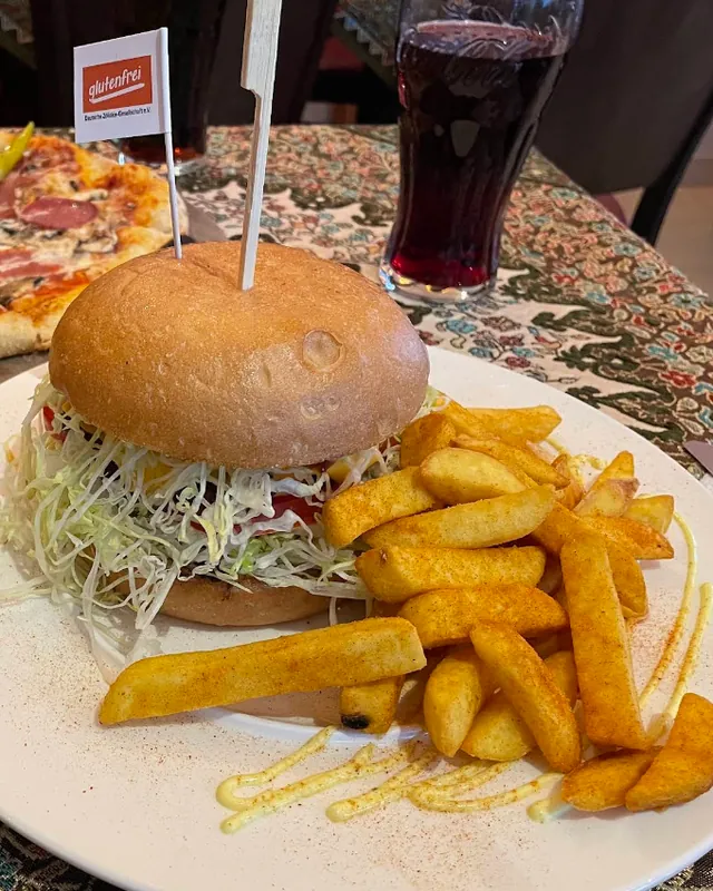 Burger mit Pommes, dahinter Pizza